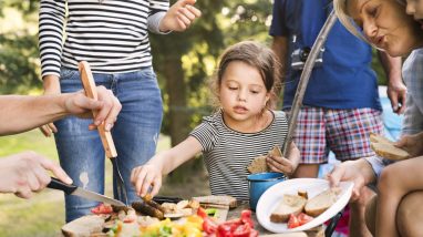 Beautiful family camping in forest, eating together.