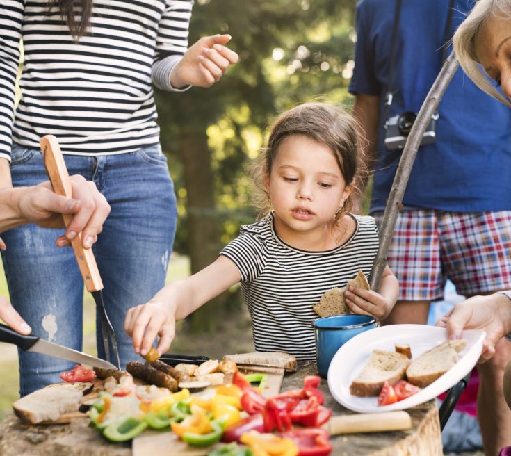 Beautiful family camping in forest, eating together.