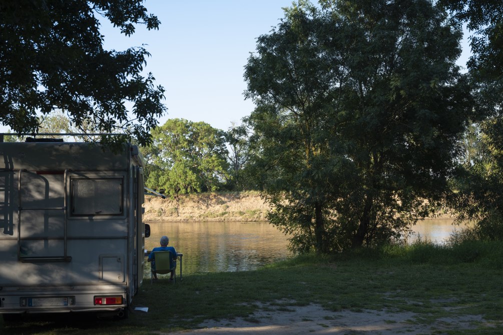 Un homme fait du camping en camping-car près d'un lac
