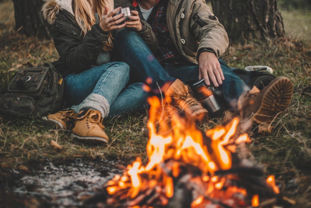 couple camping in the forest and relaxing near campfire 