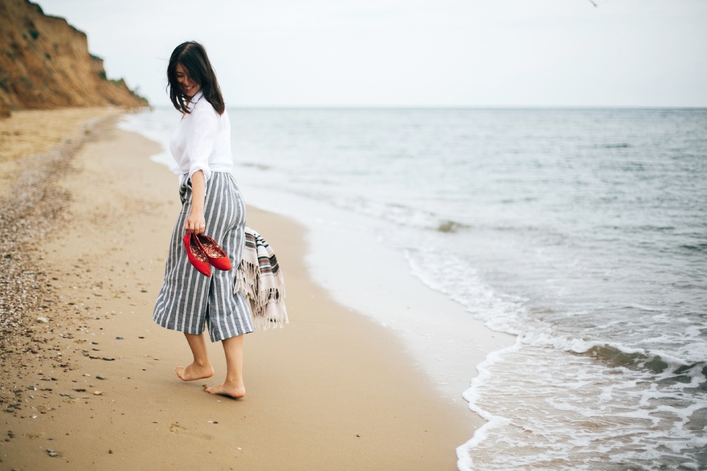 Une femme marche pieds nus sur la plage