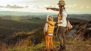 Un enfant et sa maman regardent le paysage en haut d'une montagne