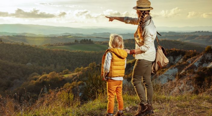 Un enfant et sa maman regardent le paysage en haut d'une montagne