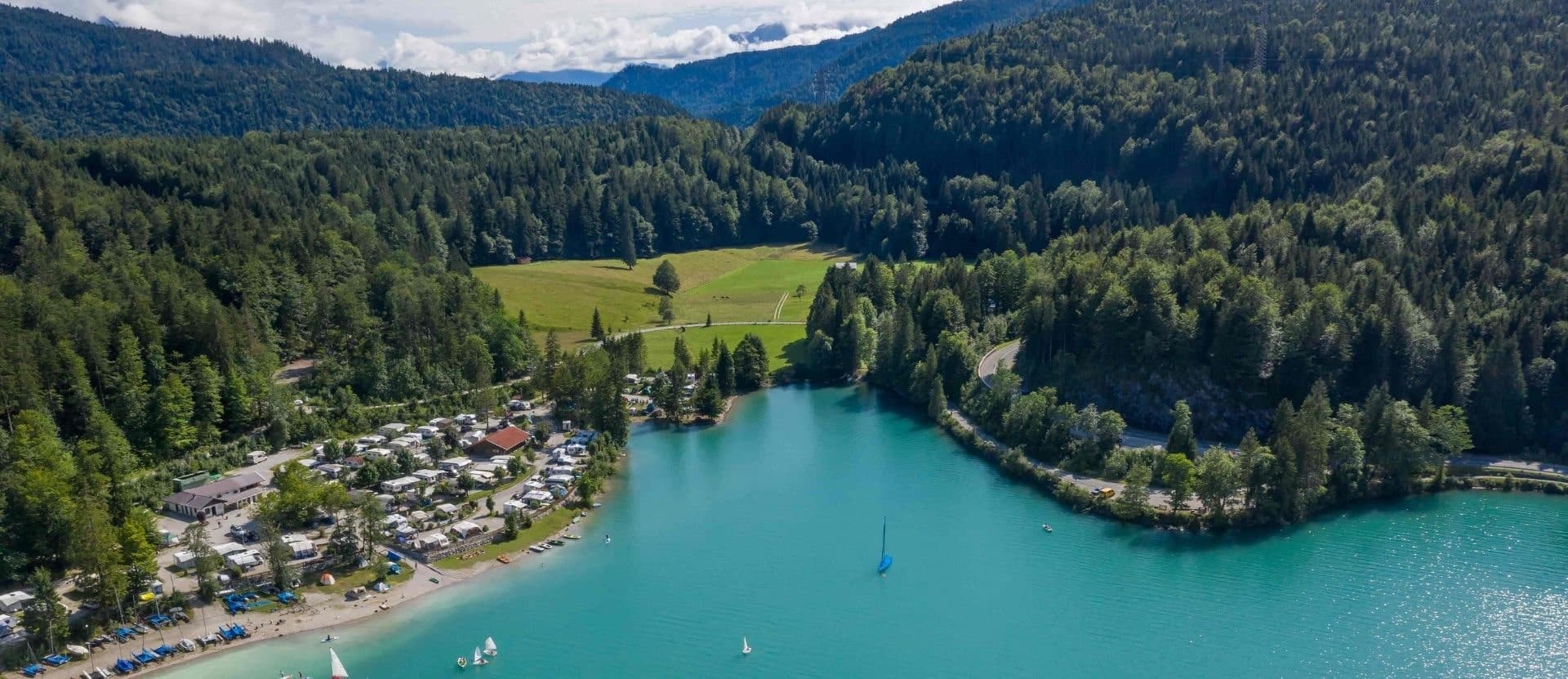 Blick auf einen schönen blauen See, umgeben von Wald und Bergen. Campingplatz in Deutschland an einem See und bewaldeten Hügeln - Campingplätze in Deutschland