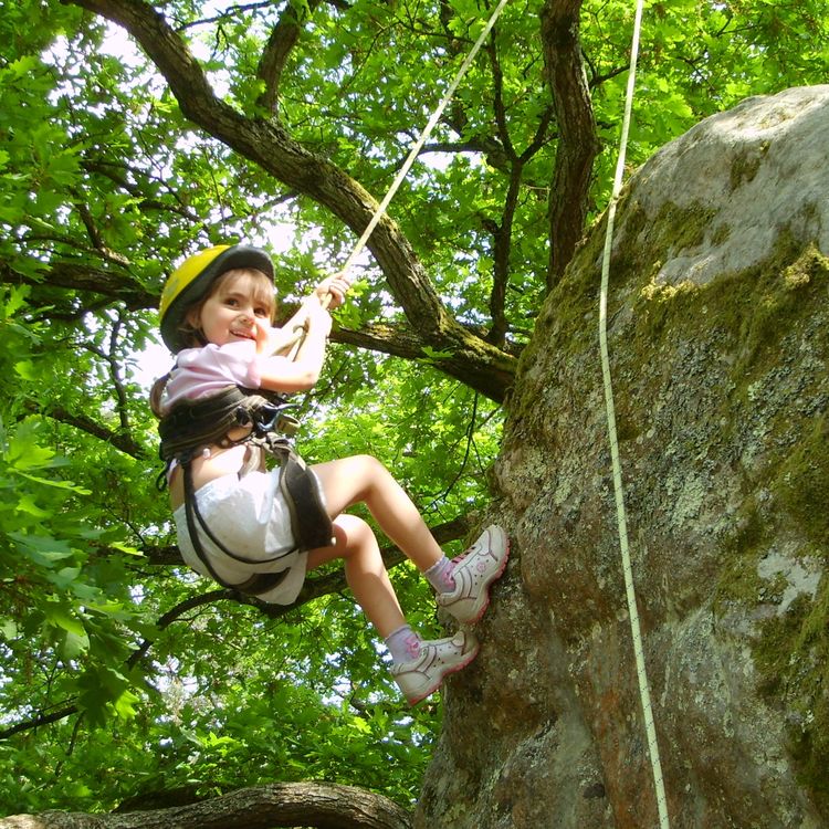 Young girl learning rock-climbing in a forest