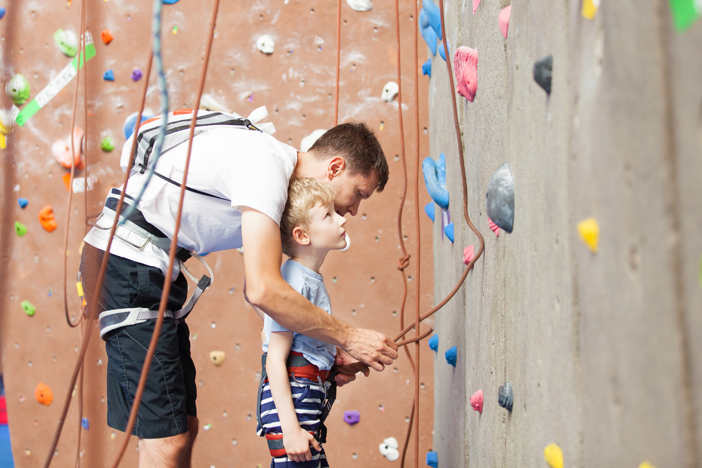 Father helping son on indoor climbing wall - Un père aide son fils sur un mur d'escalade intérieur