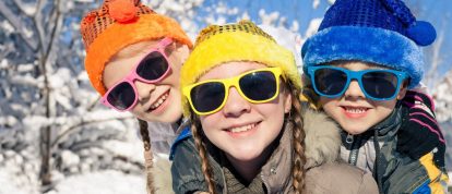 three children having fun in the snow in December