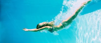 person diving into crystal clear swimming pool in summer