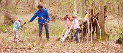 children and adults playing together in an autumnal forest