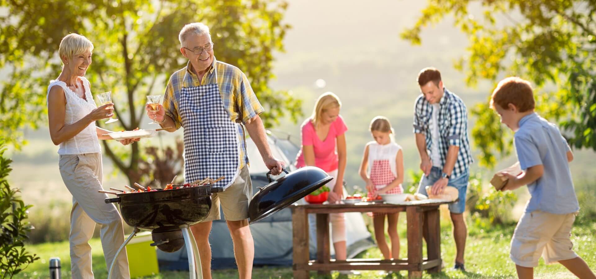 A three generation family enjoying a barbeque outdoors in a beautiful location