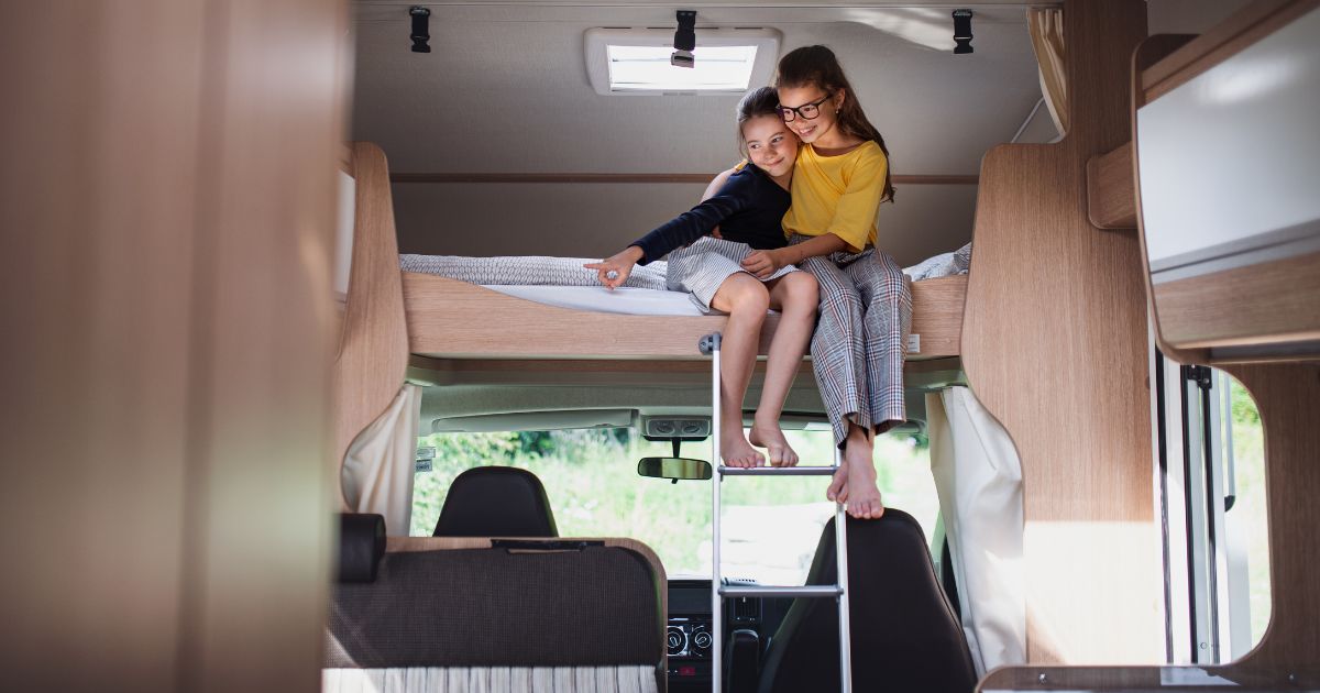 Campervan essentials for bedroom - young sisters hugging on campervan bed