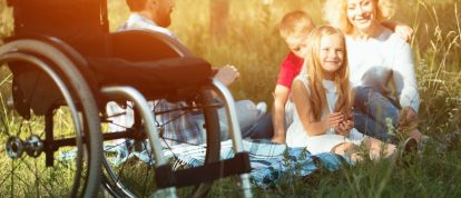 Une famille heureuse pique-niquant dans la nature dans un camping accessible aux personnes en fauteuil roulant.