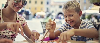 Familie genießt Pizza auf einer Piazza in Italien. Campingurlaub Angebote im August