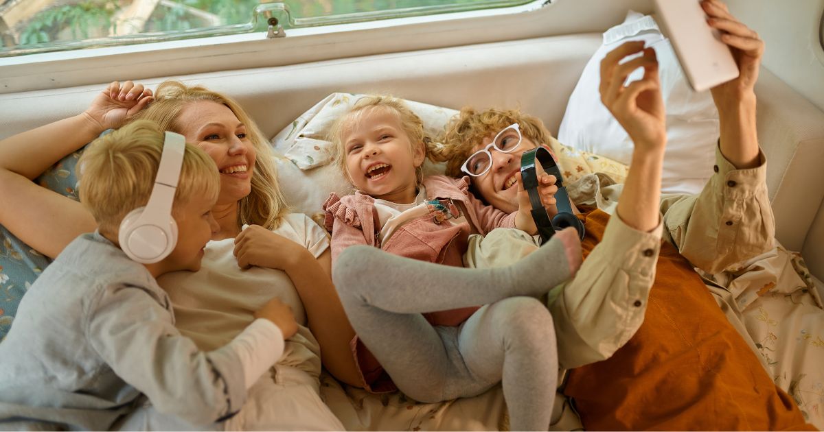 Campervan holiday entertainment - happy family in bed with headphones