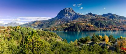 Vista panoramica del lago Serre-Poncon con Savines-le-Lac e il suo ponte con la cima del Grand Morgon in estate. Hautes-Alpes, Valle della Durance - Campeggi nelle Hautes-Alpes