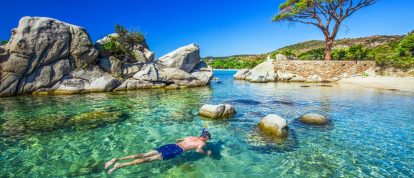 Jonge man die in een lagune met pijnboom snorkelt op het strand van Palombaggia, Corsica, Zuid Frankrijk