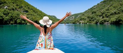 Gelukkige jonge vrouw in een waterfiets kijkt naar de rotsachtige kliffen van de Gorges du Verdon aan het meer van Sainte Croix - Campings in de Alpes-de-Haute-Provence