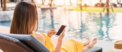 Women using mobile phone laptop on holiday by swimming pool - Campsited