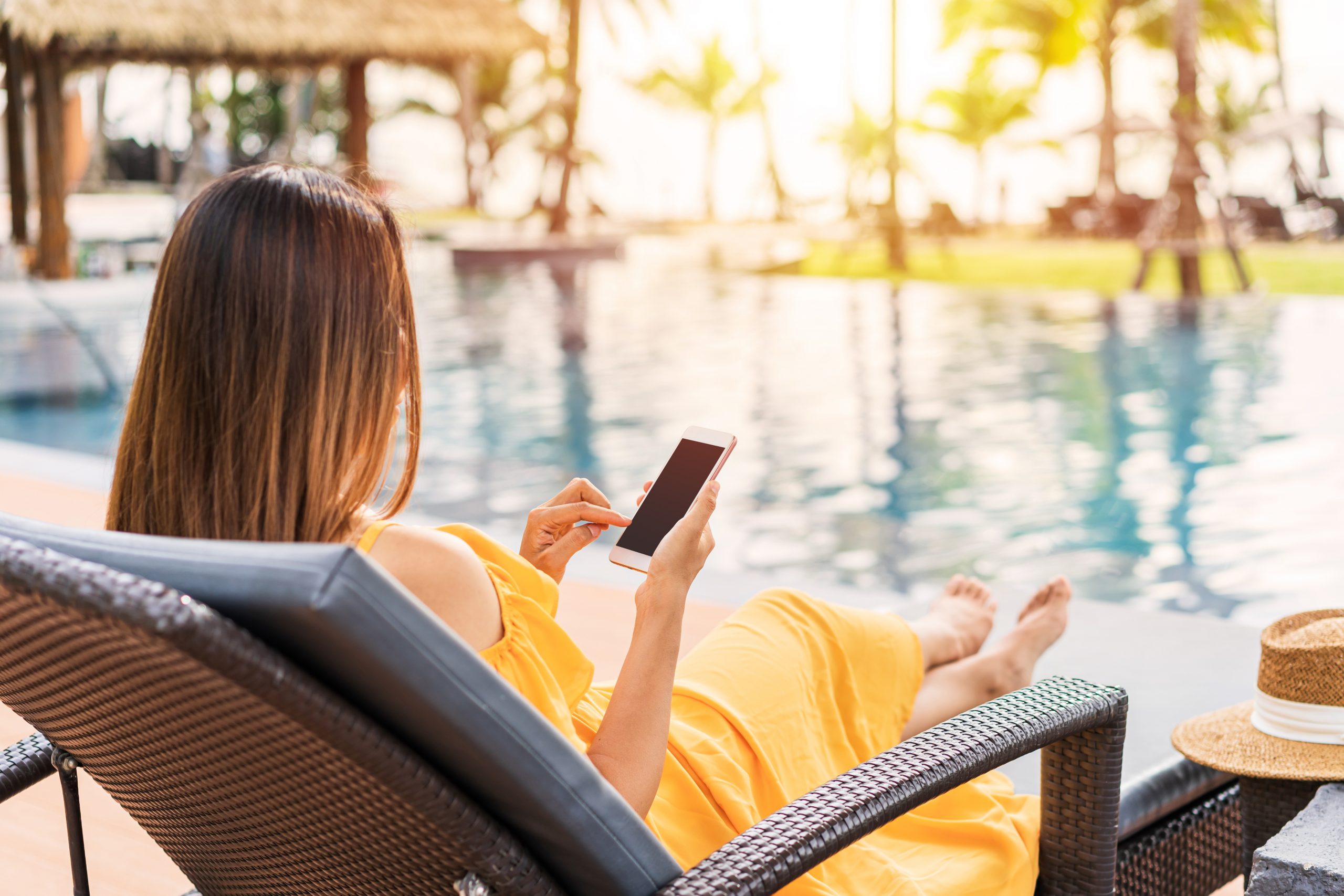 Women using mobile phone laptop on holiday by swimming pool - Campsited