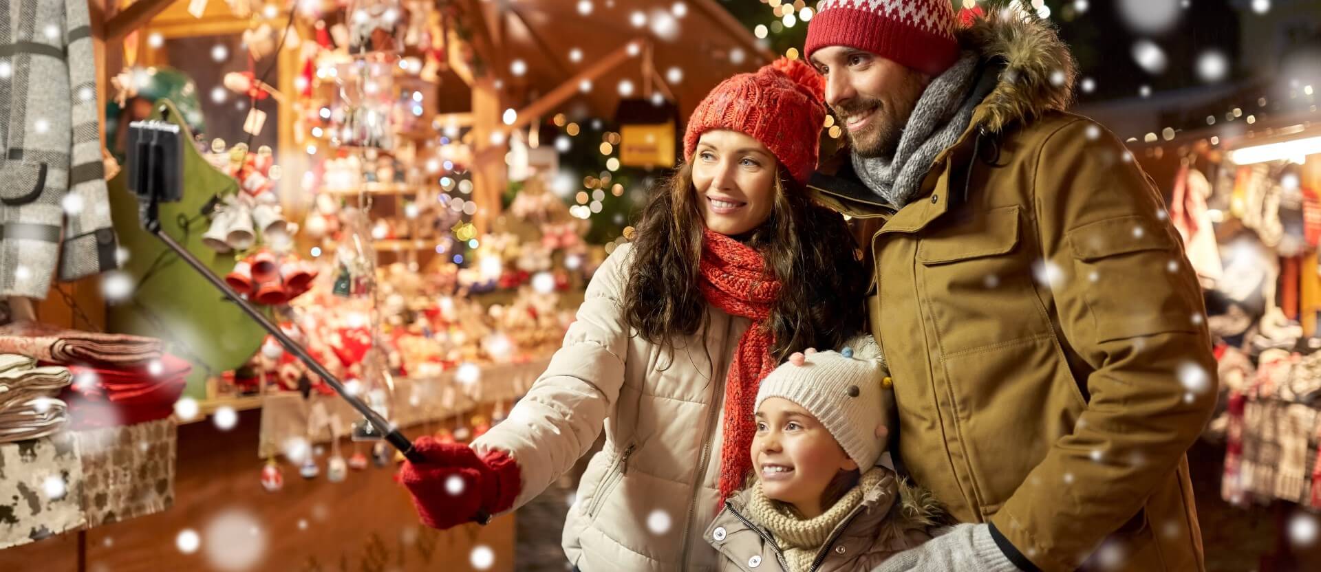 Eine Familie genießt einen magischen Moment auf einem europäischen Weihnachtsmarkt - Campingurlaub Angebote im Dezember