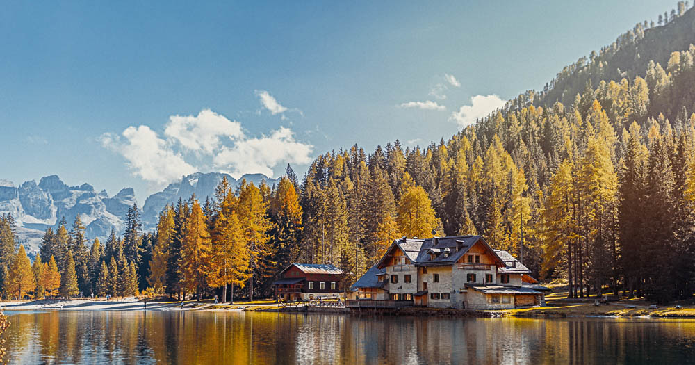 baite sul lago con alberi con foglie gialle e montagne sullo sfondo