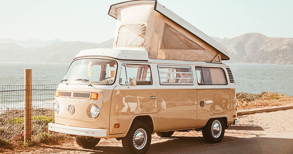 camper vintage beige con tetto apribile di fronte alla spiaggia