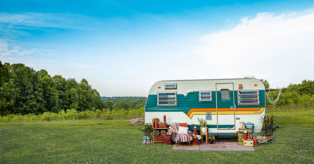 caravan con un piccolo salotto di fronte in un campo erboso