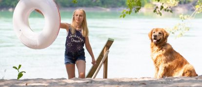 Ragazza che gioca sulla riva sabbiosa del fiume con un golden retriever - campeggi a Évreux