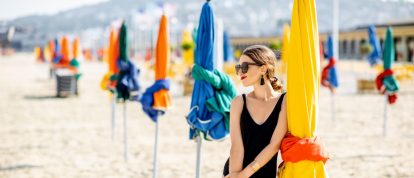 Une femme en vacances sur la plage avec des parasols colorés à Deauville, célèbre station balnéaire française en Normandie - Campings in Caen