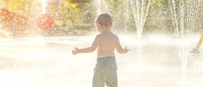 Jong kind speelt in sprinklers in waterpark - campings in Rijsel