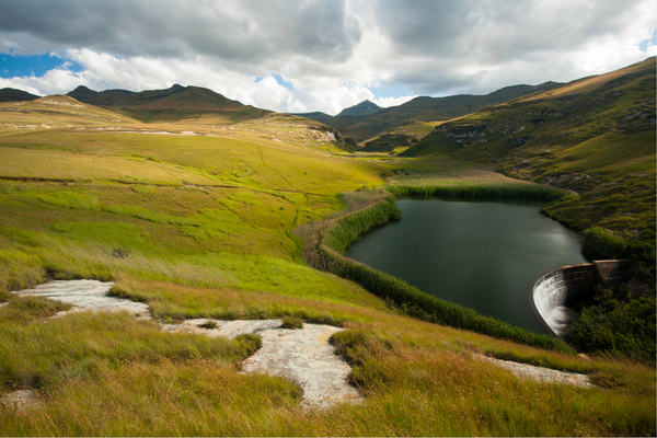 paesaggio verdeggiante con laguna e montagne sullo sfondo