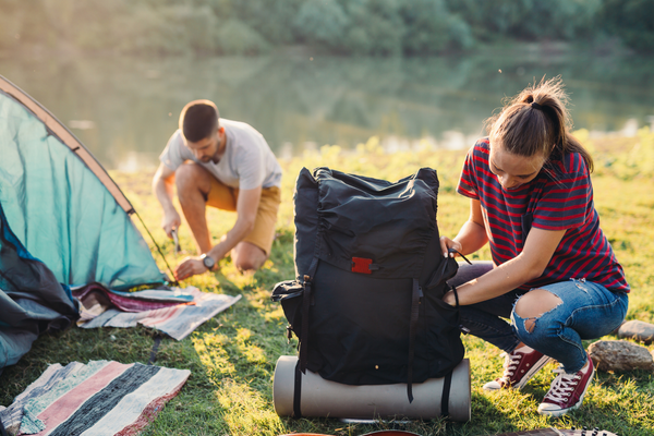 Couple setting up camping gear for day of adventure. Camping gift ideas.