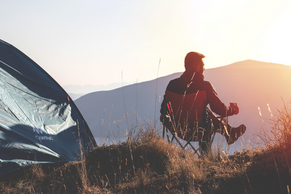 Man camping over the looking the mountains. Camping gifts for him. 