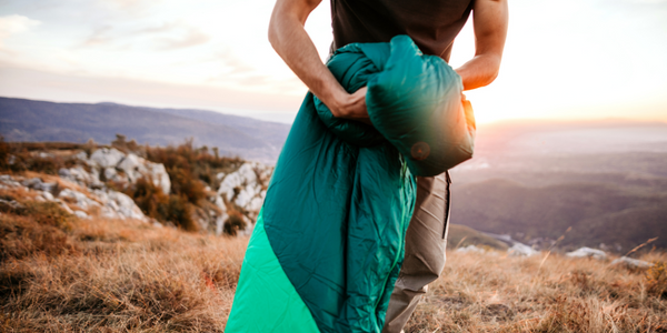 Man with sleeping bag. Best sleeping bags for camping. 
