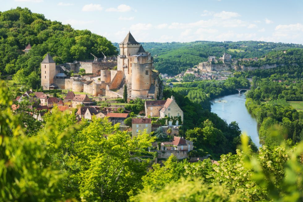 Grüne Baumwipfel geben den Ausblick frei auf Castelnaud-la-Chapelle und seine Burg in der Dordogne, Frankreich