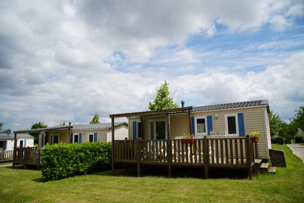 Gemütliche Mobilheime auf grünem Rasen und wolkiger blauer Himmel im Hintergrund