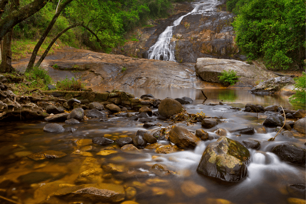 Blick auf Steine und Fluss vor einem Wasserfall im Limpopo Nationalpark, Südafrika