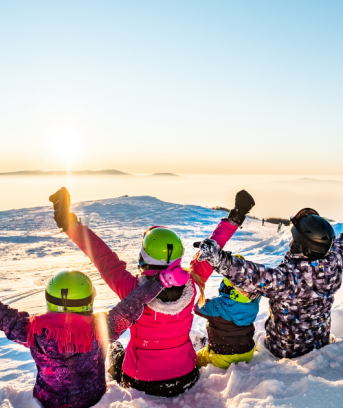 Famille assis dans la neige et contemplant le paysage au ski