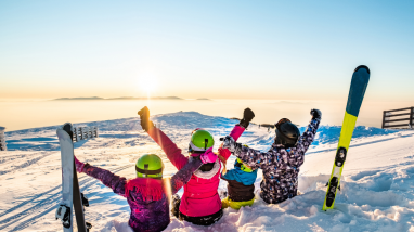 Famille assis dans la neige et contemplant le paysage au ski