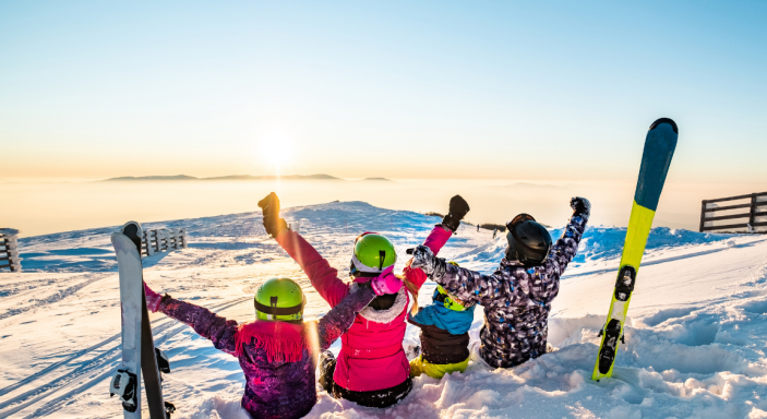 Famille assis dans la neige et contemplant le paysage au ski