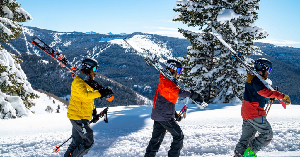 Trois personnes portant leurs skis au sein d'un superbe paysage enneigé