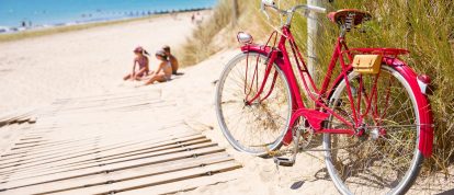 Niños en la dorada playa atlántica jugando en la arena junto a una vieja bicicleta roja - Campings en Morbihan