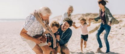 Familia de tres generaciones jugando en una playa soleada en otoño
