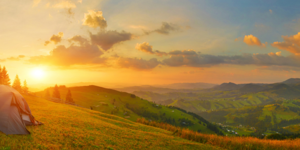 Sonnenunterang hinter einer bergigen Landschaft, Zelt auf dem Hügel