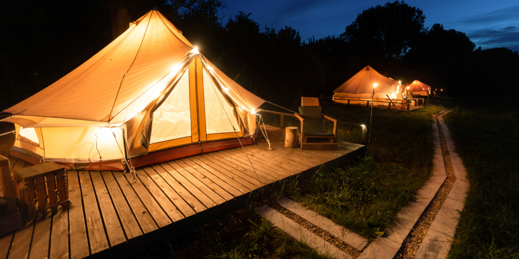 Bell tents lit up at night. Glamping village