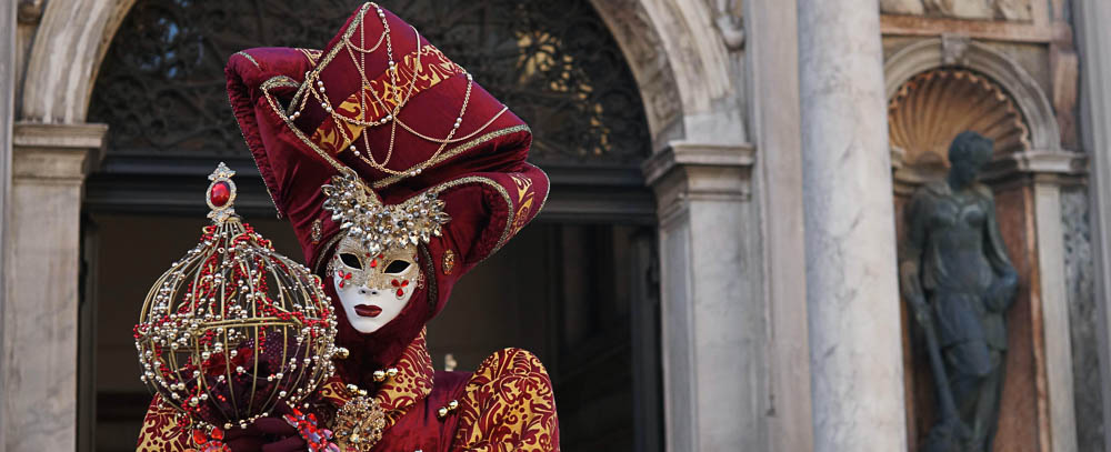 persona in maschera tradizionale affacciata a un balcone veneziano