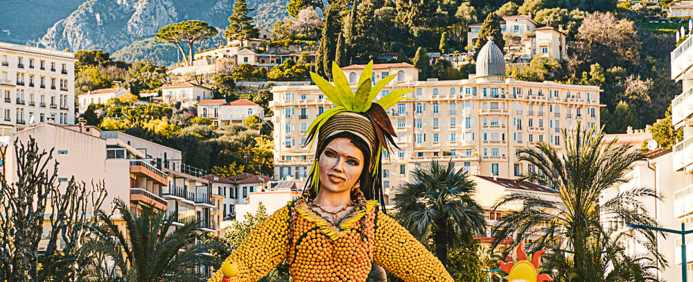 scultura di donna fatta interamente di limoni in primo piano con vista della città sullo sfondo
