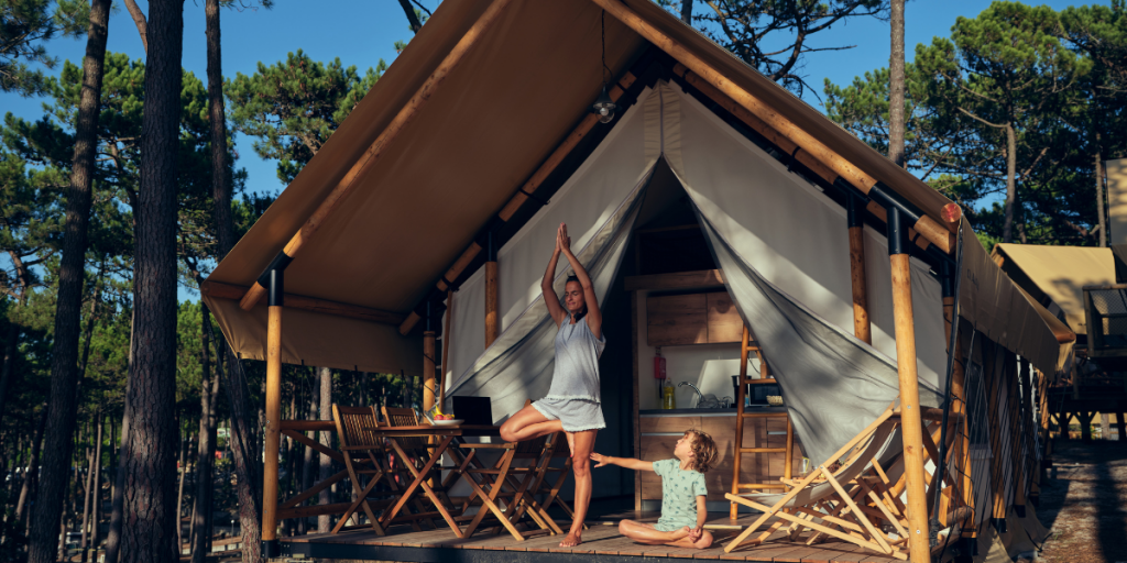 Eco-camping - Mother doing yoga on the terrace of safari-tent hut