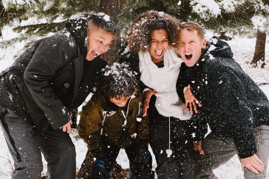 quattro amici sorridono e si abbracciano in un ambiente innevato