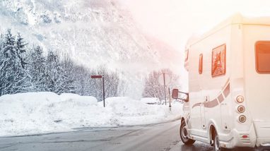 Camper sul lato della strada con paesaggio montano innevato sullo sfondo